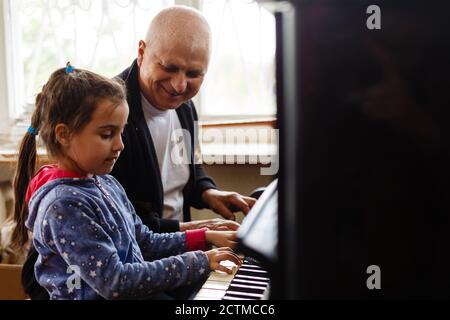 grand-père enseigner fille jouant le piano heureusement Banque D'Images