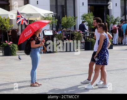 Cracovie. Cracovie. Pologne. Une femme guide tenant un parapluie avec l'inscription « Free Tour » et le drapeau britannique parlant à de jeunes toristes couple dans le Banque D'Images