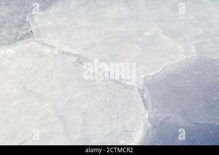Gros plan de glace fissurée sur un lac gelé en hiver, vue de face. Arrière-plan abstrait texturé plein cadre. Copier l'espace. Banque D'Images