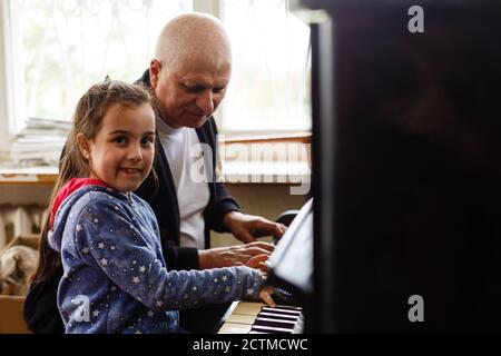 grand-père enseigner fille jouant le piano heureusement Banque D'Images