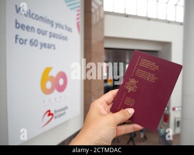 2018 août - Zaventem, Belgique : main tenue d'un passeport belge au hall d'enregistrement de l'aéroport de Bruxelles qui vient de célébrer le 60e anniversaire. Banque D'Images