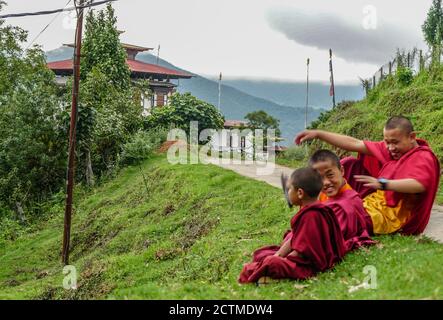 Trois moines enfants assis près de la route à Punakha, au Bhoutan Banque D'Images
