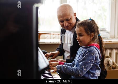 grand-père enseigner fille jouant le piano heureusement Banque D'Images