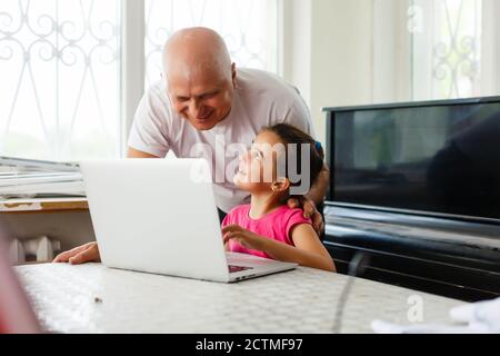 Portrait du grand-père et de la petite-fille faisant leurs devoirs avec un ordinateur portable. Banque D'Images