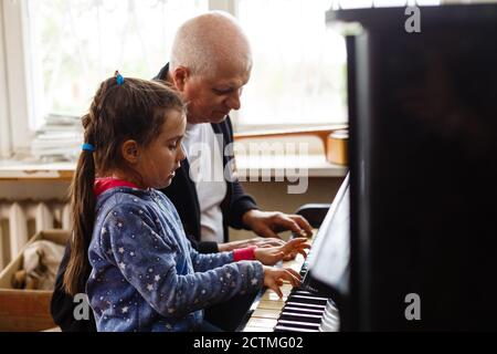 grand-père enseigner fille jouant le piano heureusement Banque D'Images