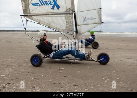 IJMUIDEN, PAYS-BAS - 17 juin 2017 : personnes qui font du vélo sur la plage sous un ciel nuageux avec la mer en arrière-plan Banque D'Images