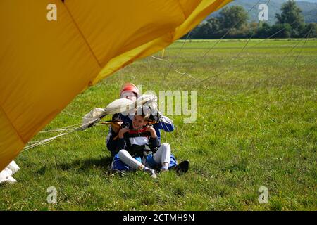 Jeune garçon et instructeur au saut en parachute en tandem peu après le moment de l'atterrissage tir coloré à Slavnica, Slovaquie, le 19 septembre 2020. Banque D'Images