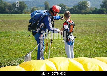 Jeune garçon et instructeur au saut en parachute en tandem peu après le moment de l'atterrissage tir coloré à Slavnica, Slovaquie, le 19 septembre 2020. Banque D'Images