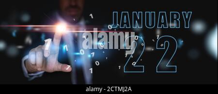 22 janvier. Jour 22 du mois, publicité ou calendrier high-tech, homme en costume appuie sur le bouton virtuel lumineux hiver mois, jour de l'année concept. Banque D'Images