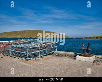 Par beau temps en été, des marmites de homard à cadre bleu empilées sur un quai prêt à l'emploi, prises à Shetland, en Écosse, au Royaume-Uni Banque D'Images