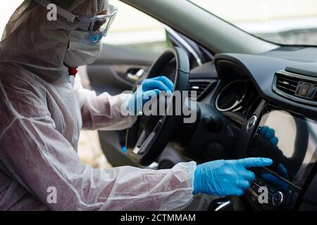 Nettoyage de l'intérieur de la voiture et pulvérisation avec du liquide de désinfection. Mains dans un gant de protection en caoutchouc désinfectant vihicule à l'intérieur pour la protection contre les virus Banque D'Images
