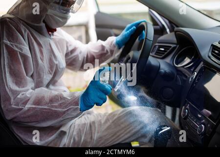 Nettoyage de l'intérieur de la voiture et pulvérisation avec du liquide de désinfection. Mains dans un gant de protection en caoutchouc désinfectant vihicule à l'intérieur pour la protection contre les virus Banque D'Images