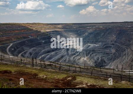 Carrière géante de minerai de fer à ciel ouvert à Rudny, Kazakhstan. Extraction de minéraux bruts pour la production d'acier. Vue panoramique. Chemin de fer au premier plan. Ciel bleu avec cl Banque D'Images