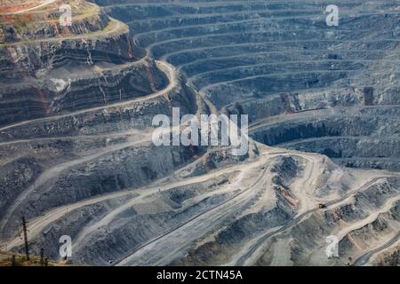 Extraction à ciel ouvert de minéraux bruts pour la production d'acier. Carrière de minerai de fer géant à Rudny, Kazakhstan. Couches géologiques et petit camion de carrière jaune vers le bas. Banque D'Images