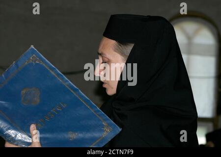 Jeune nonne dans un monastère chrétien orthodoxe en Roumanie lisant d'un livre religieux Banque D'Images