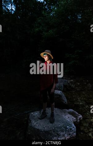 Femme touriste debout sur le rocher dans les bois la nuit et recherche d'itinéraire en utilisant la carte numérique sur le téléphone portable Banque D'Images