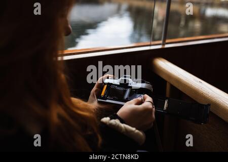 Vue latérale de la récolte une femme non reconnaissable insère un rouleau de film dans un appareil photo à l'ancienne lors d'une excursion en bateau sur le lac en automne Banque D'Images