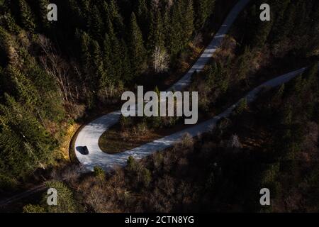 De dessus vue aérienne de voiture solitaire sur asphalte curvy chaussée en pente de montagne couverte de forêt de conifères verts Banque D'Images