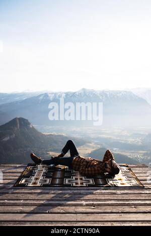 touriste mâle méconnaissable allongé sur une couverture au point de vue et appréciant paysage de crête de montagne le matin Banque D'Images