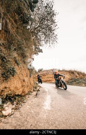 motards non reconnaissables qui conduisent des motos sur une route asphaltée étroite traverser un terrain montagneux Banque D'Images