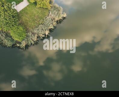 Vue de haut en bas sur le lac et les ruelles du parc avec reflet des nuages. Drone, vue aérienne Banque D'Images