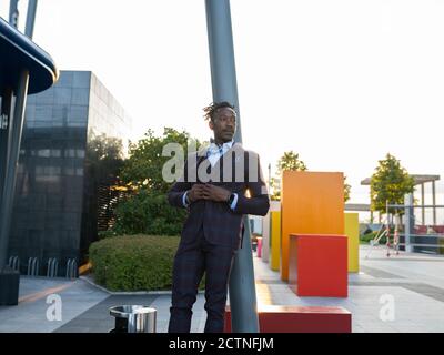 Faible angle d'un homme d'affaires afro-américain sérieux, vêtu de classe vous vous penchez au feu de la rue dans le centre-ville et vue sur l'extérieur Banque D'Images