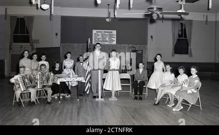 Début des années 1950, photo historique des enfants assis dans une ligne dans une salle, certains tenant des trophées, ayant participé à un concours de danse musicale, qui étaient populaires à cette époque. Le panneau pour 'Programme de danse', énumère les danses traditionnelles de 27, y compris la Waltz, deux pas et Polka. Un avis sur le piano dit «c'est une danse du temps ancien» aucune danse de jitterbug permis! Banque D'Images