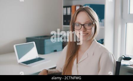 Portrait d'une jeune femme handicapée dans le bureau souriant vers l'appareil photo. Photo de haute qualité Banque D'Images