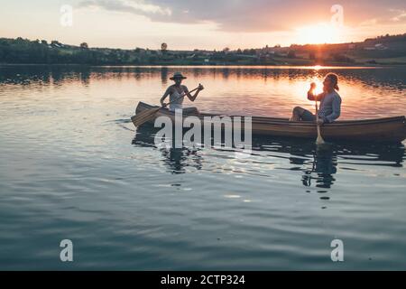 Couple romantique en canoë sur le lac au coucher du soleil Banque D'Images