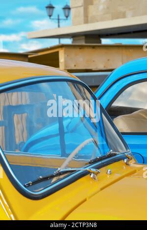 Capot et pare-brise d'une voiture jaune sur le fond d'un gros plan de voiture bleue. Banque D'Images
