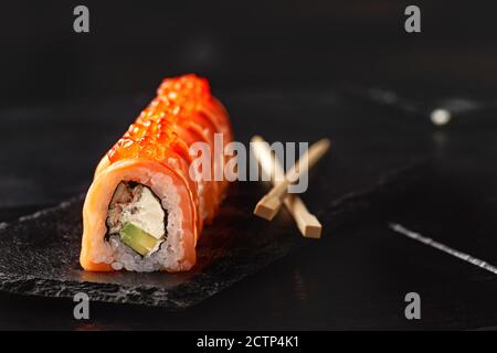 Sushi roll maki futo cuisine japonaise sur une assiette en pierre noire dans les mains d'un serveur. Gros plan Banque D'Images