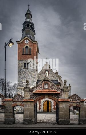 Ancienne église en pierre et en brique avec tour d'horloge à Bialka Tatrzanska. Nuages sombres et sombres et ciel spectaculaire. Montagnes Tatra, Pologne Banque D'Images