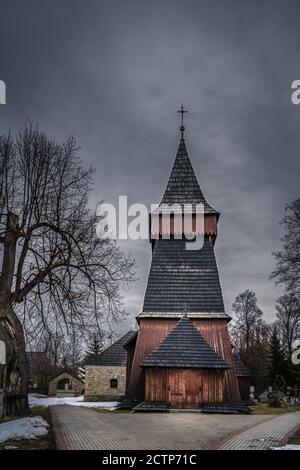 Unique église en bois du XVIIe siècle à Bialka Tatrzanska. Nuages sombres et sombres et ciel spectaculaire. Montagnes Tatra, Pologne Banque D'Images