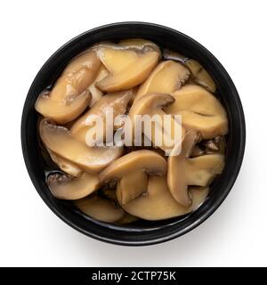 Champignons de Paris tranchés en conserve dans un bol en céramique noire isolé sur blanc. Vue de dessus. Banque D'Images