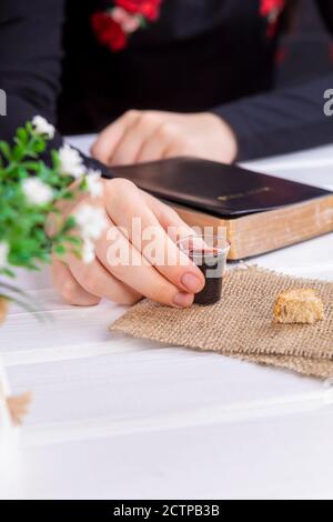 Jeune femme priant et prenant la communion - le vin et les symboles du pain de Jésus Christ sang et corps avec la Sainte Bible. Pâque de Pâques et Seigneur su Banque D'Images