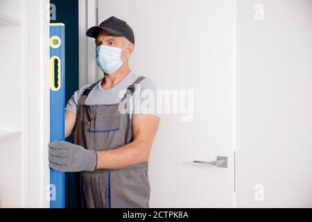 Ouvrier de menuisier dans le processus de masque médical installation de bois de porte Banque D'Images