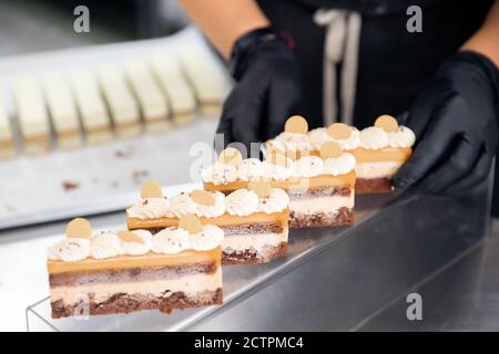 Le chef pâtissier tient des pinces à noix et décorera les gâteaux avant de servir au restaurant. Concept de haute cuisine Banque D'Images