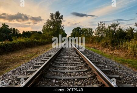 De vieilles voies ferrées traversant la campagne avec un magnifique ciel de coucher de soleil à Rastatt, en Allemagne Banque D'Images