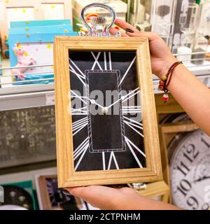 Femme tenant une grande horloge murale au magasin Banque D'Images