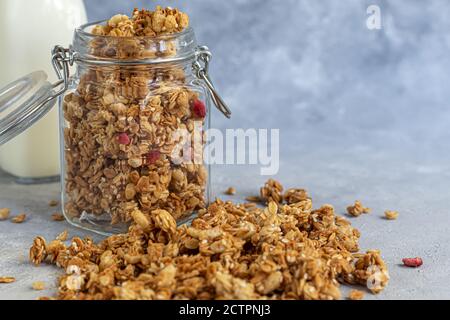 Granola maison avec tranches de fraise dans un pot en verre. Sur fond gris. Plat végétarien. Petit déjeuner sain. Copier l'espace. Banque D'Images