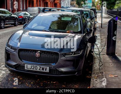 Point de recharge de voiture électrique dans la rue à South Kensington, Londres ; voiture Jaguar en cours de recharge. Banque D'Images