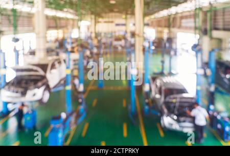 Arrière-plan flou du technicien réparant la voiture dans le garage, mécanique fixant dans un atelier détail de suspension de l'automobile soulevée à la station-service, Banque D'Images