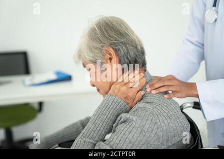 Femme âgée souffrant de douleurs au cou dans le bureau médical, femme sénior malade avec douleur au dos du cou et des épaules sur les articulations et les muscles. Banque D'Images