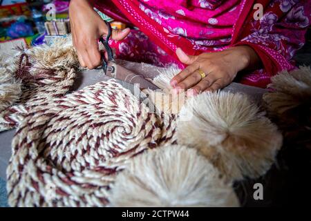 Une femme qui fait de l'artisanat lisse les fibres d'un bananière avec des ciseaux à Madhupur, Tangail, Bangladesh. Banque D'Images