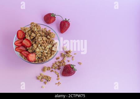 Granola maison avec tranches de fraise sur fond rose. Plat végétarien. Petit déjeuner sain. Copier l'espace. Banque D'Images