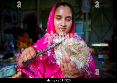 Une femme qui fait de l'artisanat lisse les fibres d'un bananière avec des ciseaux à Madhupur, Tangail, Bangladesh. Banque D'Images