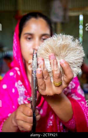 Une femme qui fait de l'artisanat lisse les fibres d'un bananière avec des ciseaux à Madhupur, Tangail, Bangladesh. Banque D'Images