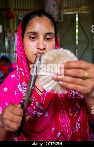 Une femme qui fait de l'artisanat lisse les fibres d'un bananière avec des ciseaux à Madhupur, Tangail, Bangladesh. Banque D'Images