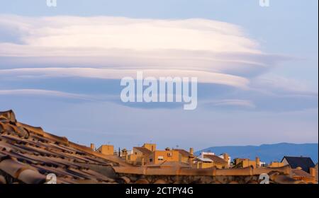 Grands nuages lenticulaires sur les toits des maisons résidentielles dans un logement au coucher du soleil Banque D'Images