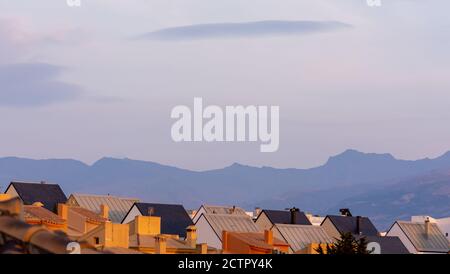 Grands nuages lenticulaires sur les toits des maisons résidentielles dans un logement au coucher du soleil Banque D'Images